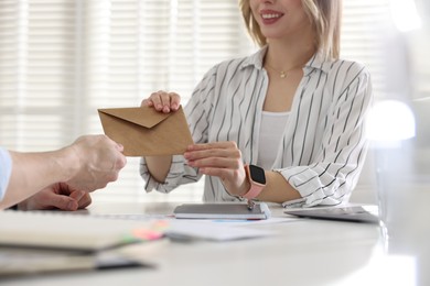 Photo of Money bonus. Employee receiving envelope from boss in office, closeup