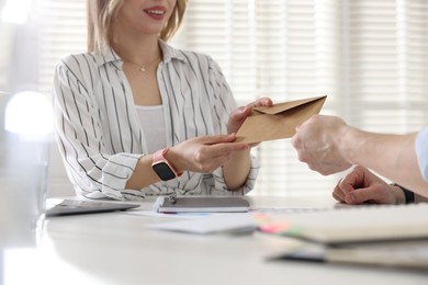 Photo of Money bonus. Employee receiving envelope from boss in office, closeup