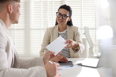 Photo of Money bonus. Employee receiving envelope from boss in office