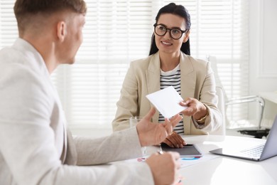 Photo of Money bonus. Employee receiving envelope from boss in office
