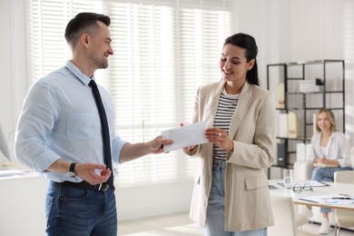 Photo of Money bonus. Boss giving envelope to employee in office