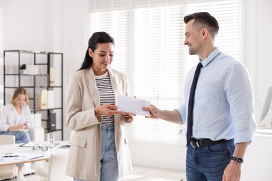 Photo of Money bonus. Boss giving envelope to employee in office