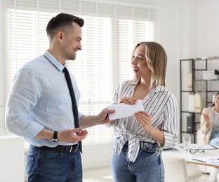 Photo of Money bonus. Boss giving envelope to employee in office