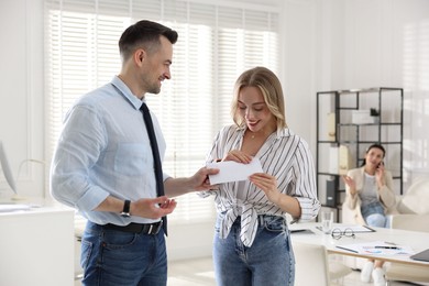 Photo of Money bonus. Boss giving envelope to employee in office