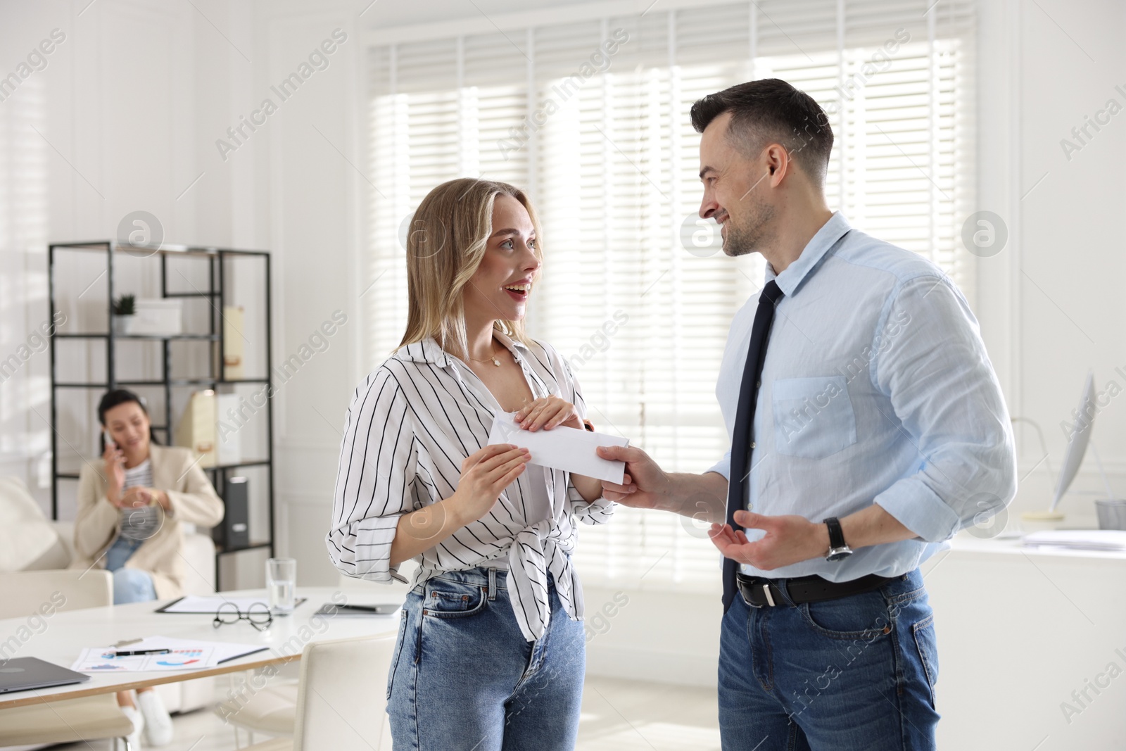 Photo of Money bonus. Boss giving envelope to employee in office