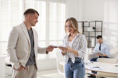 Photo of Money bonus. Boss giving envelope to employee in office