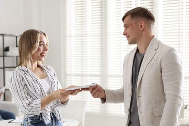 Photo of Money bonus. Boss giving envelope to employee in office