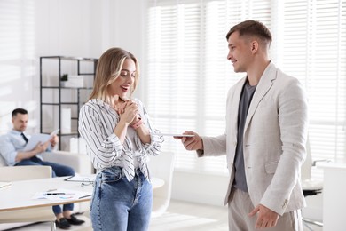 Photo of Money bonus. Boss giving envelope to employee in office