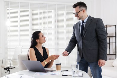 Photo of Money bonus. Boss giving envelope to employee in office