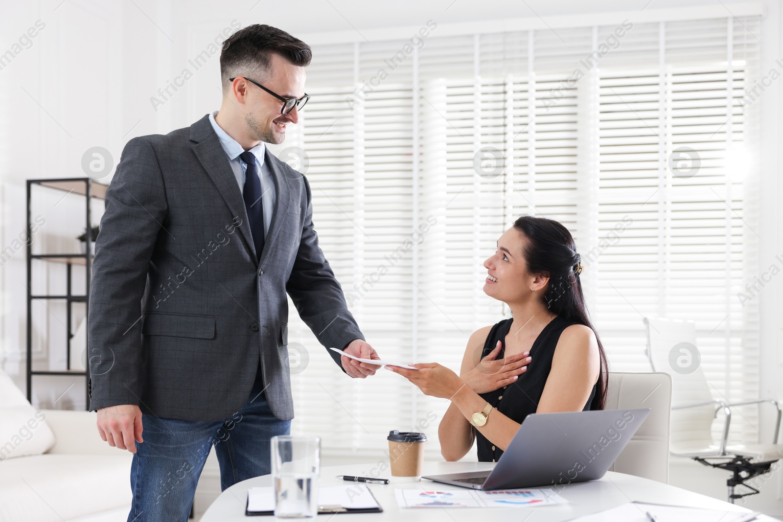 Photo of Money bonus. Boss giving envelope to employee in office