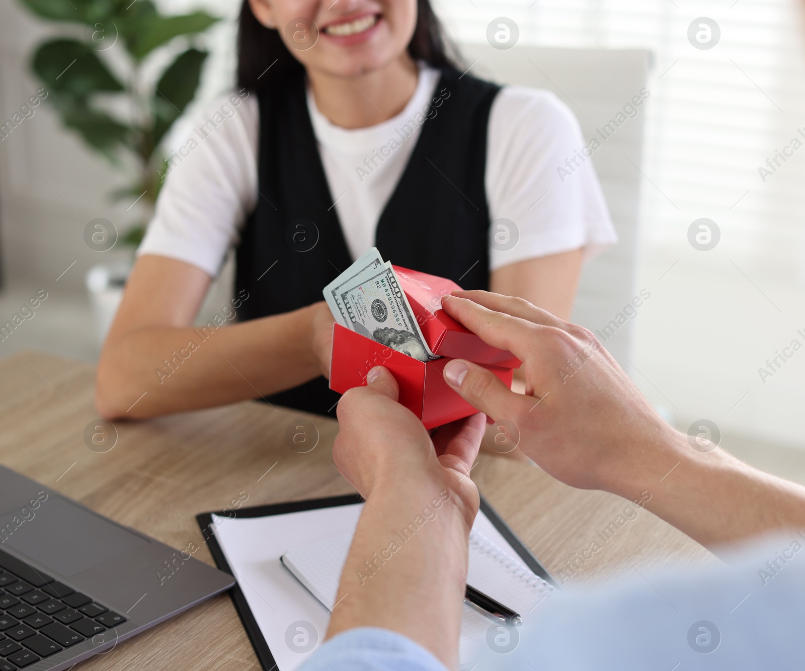 Bonus. Boss giving box with money to employee in office, closeup Photo of Bonus. Boss giving box with money to employee in office, closeup