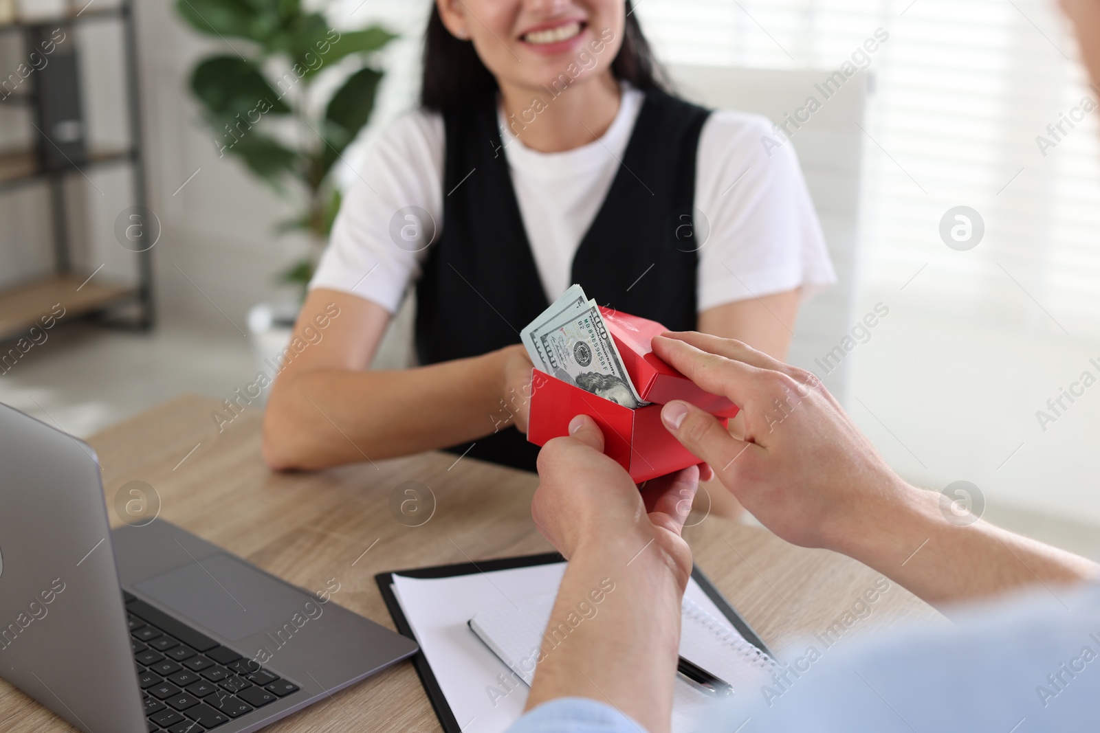 Bonus. Boss giving box with money to employee in office, closeup Photo of Bonus. Boss giving box with money to employee in office, closeup