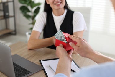 Photo of Bonus. Boss giving box with money to employee in office, closeup