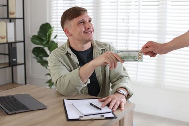 Photo of Bonus. Employee receiving money from boss in office