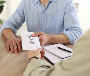 Photo of Boss giving envelope with word bonus to employee in office, closeup