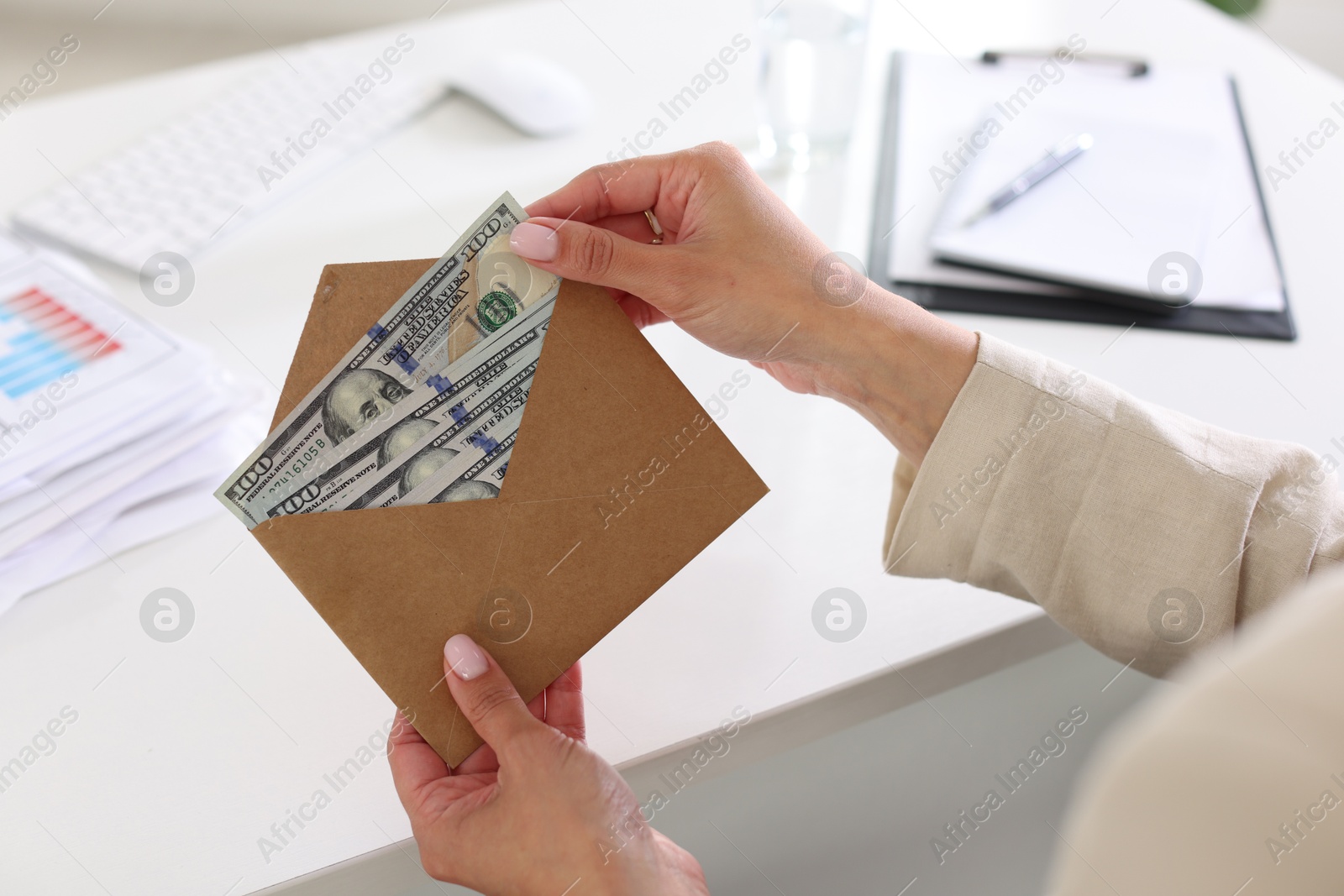 Bonus. Woman holding envelope with money at desk in office, closeup Photo of Bonus. Woman holding envelope with money at desk in office, closeup