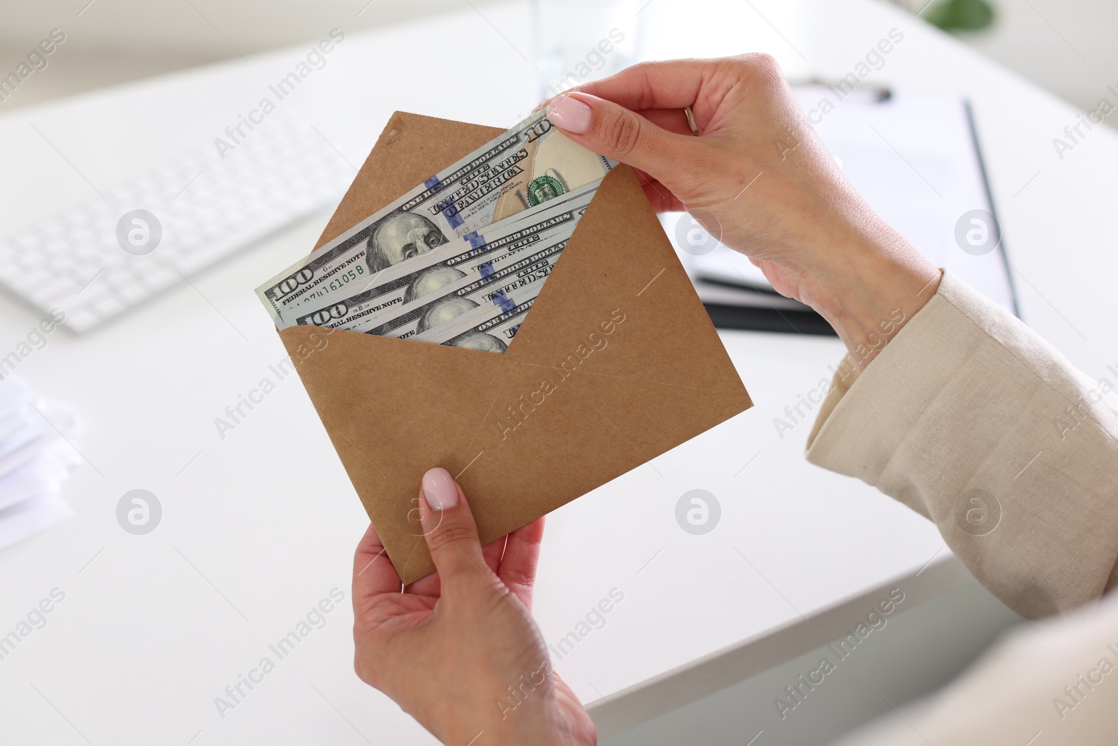Bonus. Woman holding envelope with money at desk in office, closeup Photo of Bonus. Woman holding envelope with money at desk in office, closeup