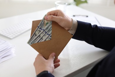 Photo of Bonus. Man holding envelope with money at desk in office, closeup
