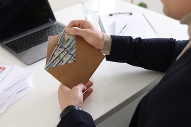 Photo of Bonus. Man holding envelope with money at desk in office, closeup