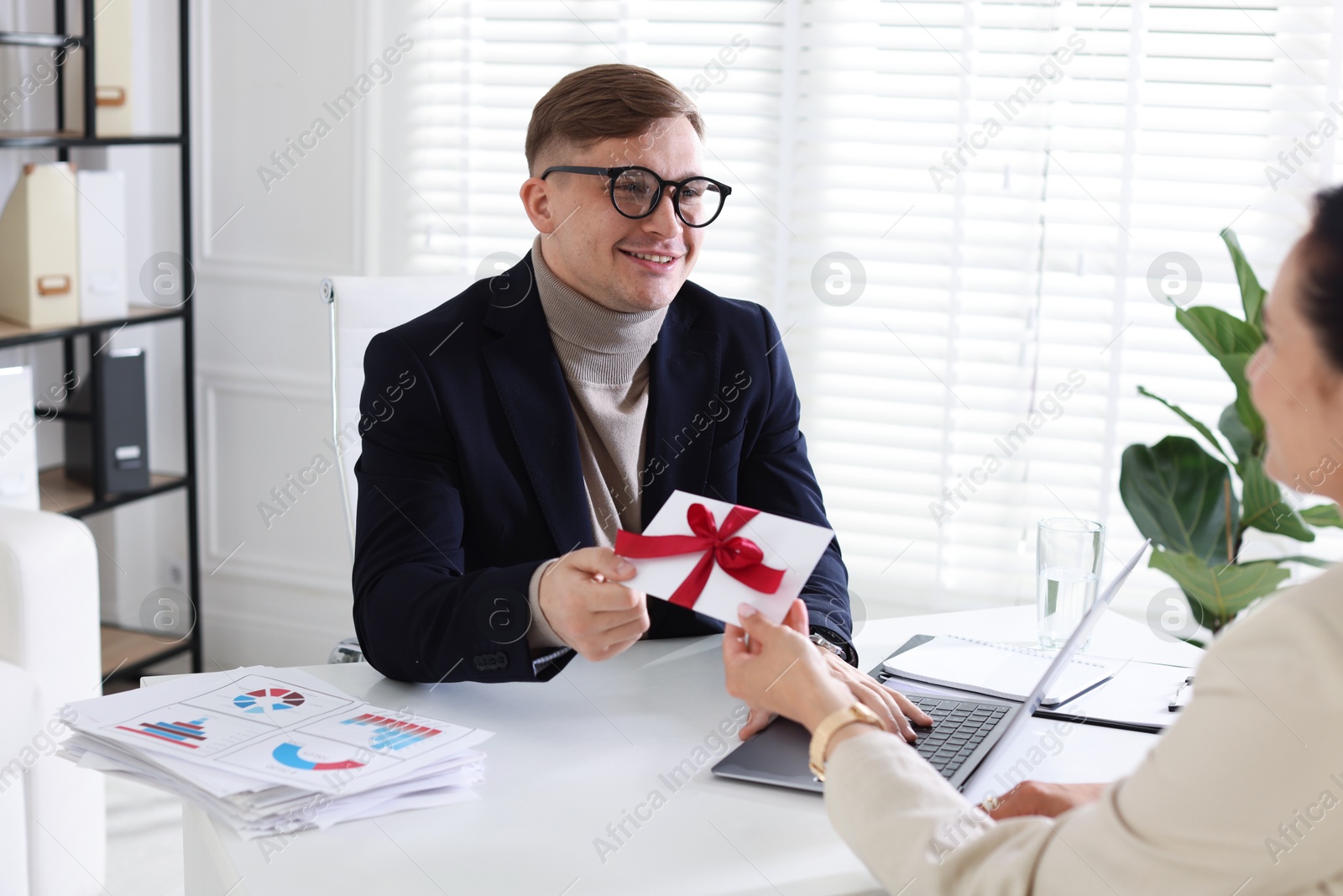 Money bonus. Employee receiving envelope with bow from boss in office Photo of Money bonus. Employee receiving envelope with bow from boss in office