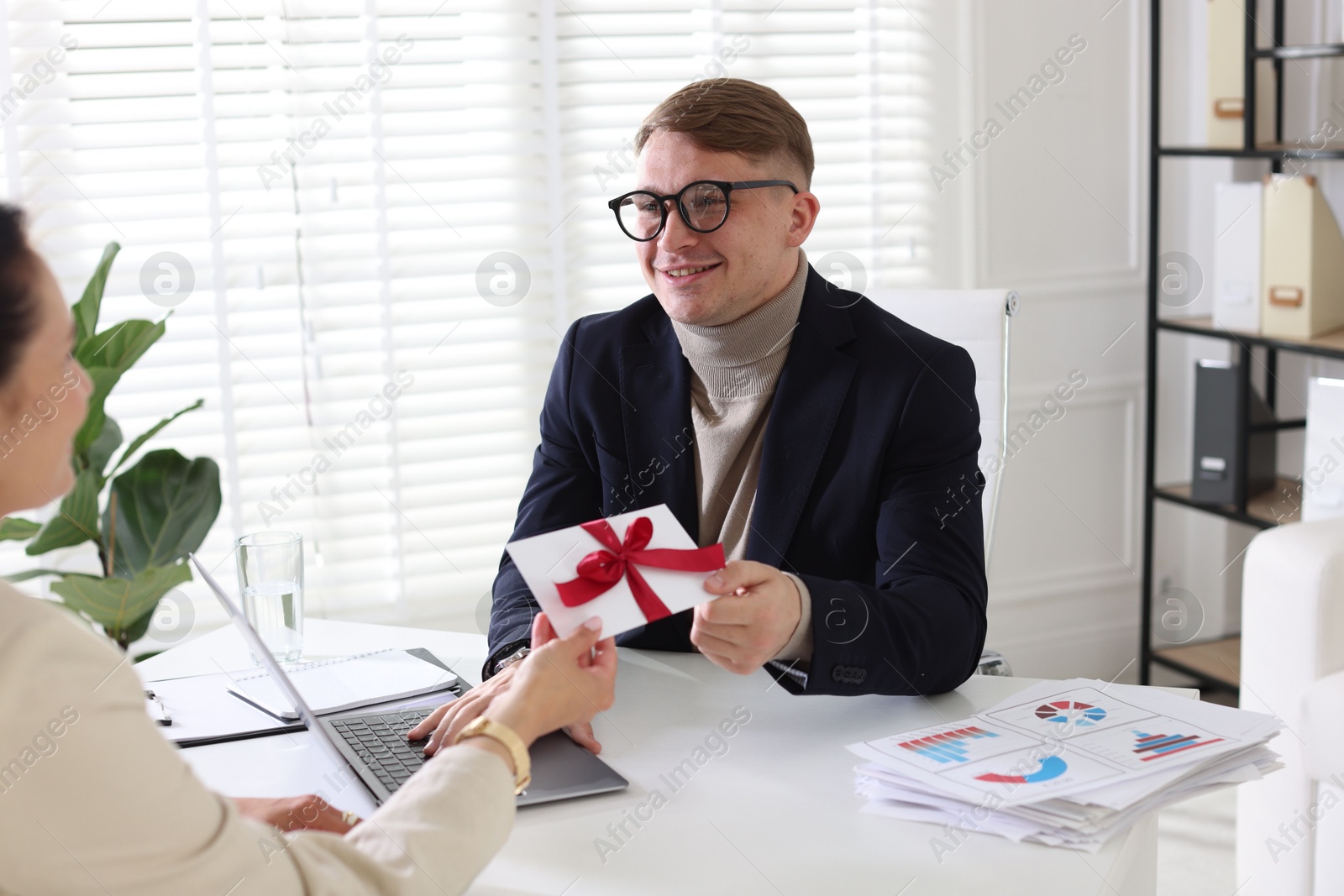 Money bonus. Employee receiving envelope with bow from boss in office Photo of Money bonus. Employee receiving envelope with bow from boss in office