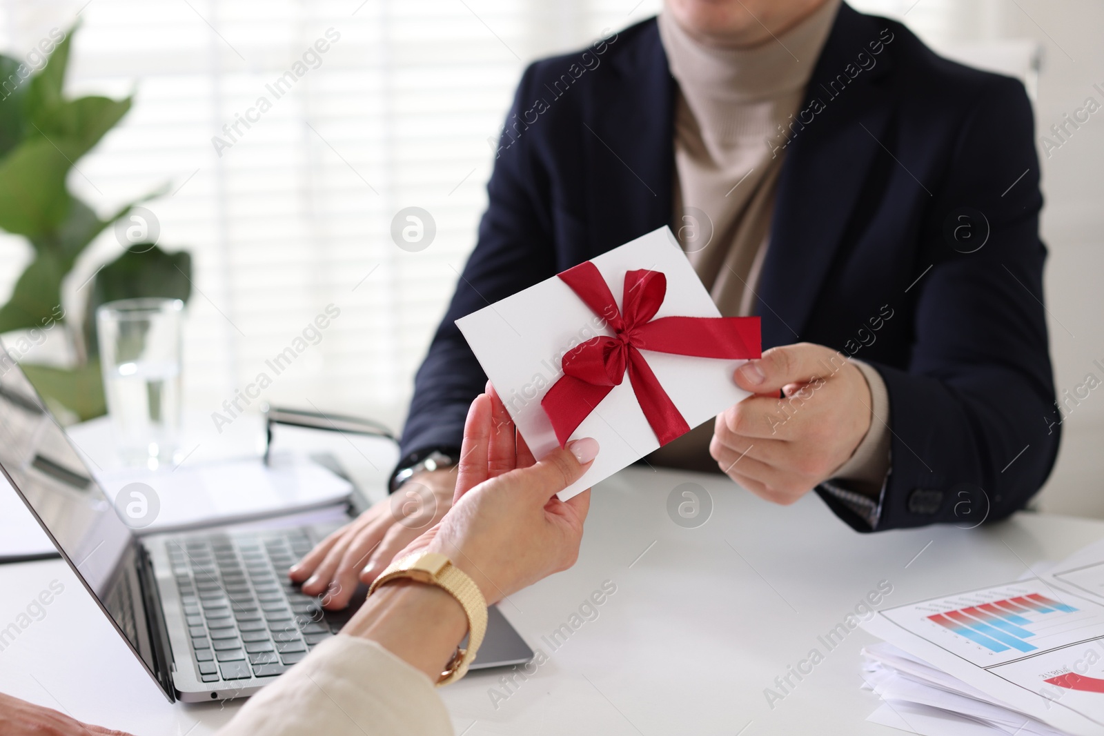Money bonus. Employee receiving envelope with bow from boss in office, closeup Photo of Money bonus. Employee receiving envelope with bow from boss in office, closeup