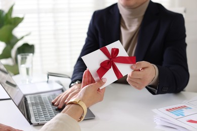 Photo of Money bonus. Employee receiving envelope with bow from boss in office, closeup