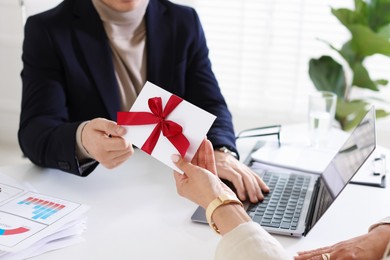 Photo of Money bonus. Employee receiving envelope with bow from boss in office, closeup
