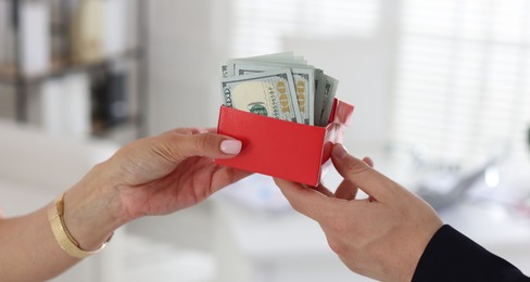 Photo of Bonus. Boss giving box with money to employee in office, closeup