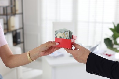 Photo of Bonus. Boss giving box with money to employee in office, closeup