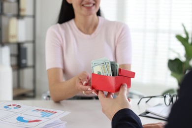 Photo of Bonus. Employee receiving box with money from boss in office, closeup
