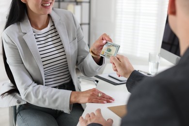Photo of Bonus. Boss giving money to employee in office, closeup