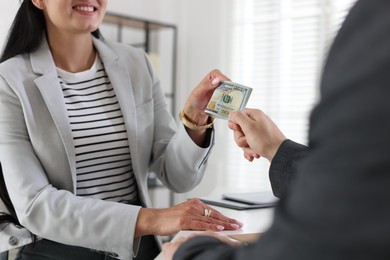 Photo of Bonus. Boss giving money to employee in office, closeup