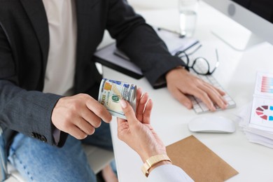 Photo of Bonus. Boss giving money to employee in office, closeup