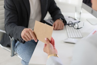 Photo of Money bonus. Boss giving envelope to employee in office, closeup