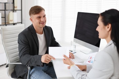 Photo of Money bonus. Employee receiving envelope from boss in office