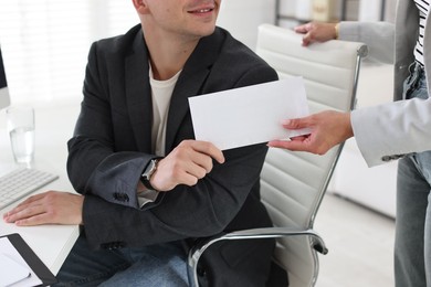Photo of Money bonus. Employee receiving envelope from boss in office, closeup