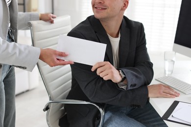 Photo of Money bonus. Employee receiving envelope from boss in office, closeup