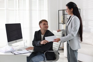 Photo of Money bonus. Employee receiving envelope from boss in office