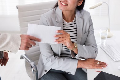 Photo of Money bonus. Employee receiving envelope from boss in office, closeup