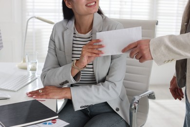 Photo of Money bonus. Employee receiving envelope from boss in office, closeup