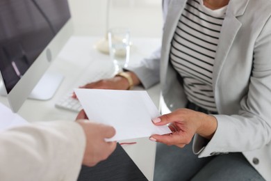 Photo of Money bonus. Employee receiving envelope from boss in office, closeup