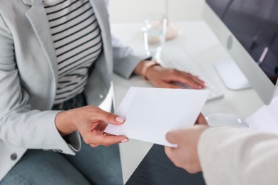 Photo of Money bonus. Employee receiving envelope from boss in office, closeup