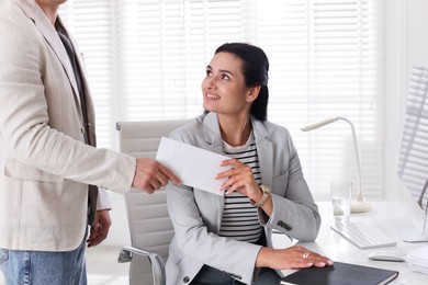 Photo of Money bonus. Employee receiving envelope from boss in office