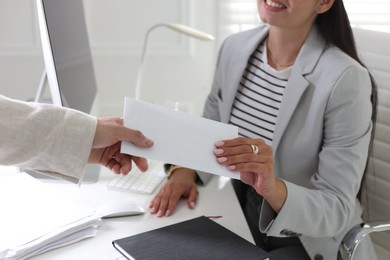 Photo of Money bonus. Employee receiving envelope from boss in office, closeup