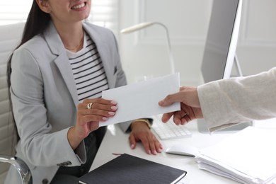 Photo of Money bonus. Employee receiving envelope from boss in office, closeup