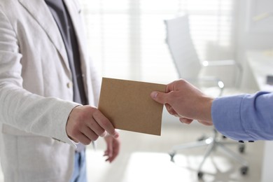 Photo of Money bonus. Employee receiving envelope from boss in office, closeup