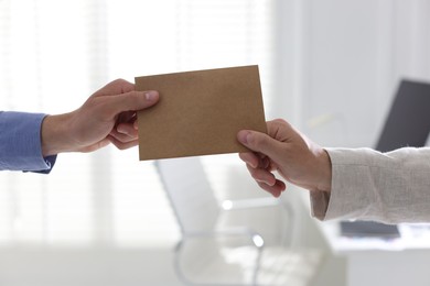 Photo of Money bonus. Employee receiving envelope from boss in office, closeup