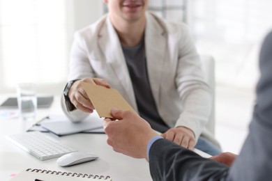 Photo of Money bonus. Employee receiving envelope from boss in office, closeup