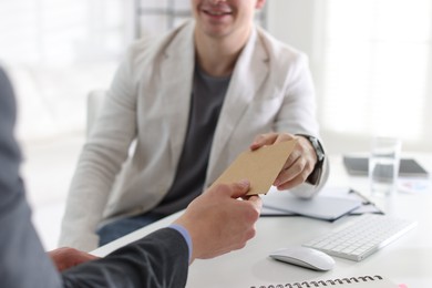 Photo of Money bonus. Employee receiving envelope from boss in office, closeup